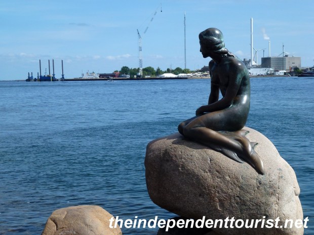 The Little Mermaid contemplates life sitting on a rock right next to the shore.