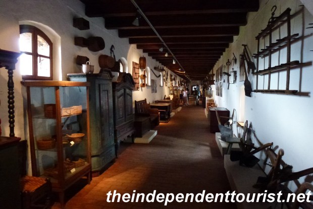 The elevated hall leading to the Latrine Tower, with many displays of old farm tools and home furnishings.