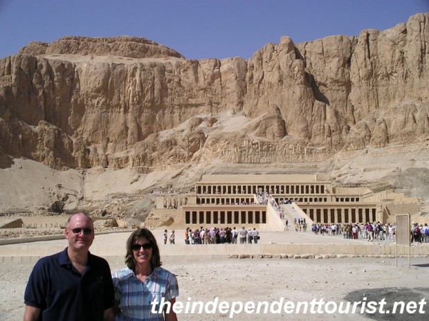 The Temple of Hatshepsut at the base of a dramtic limestone cliff.